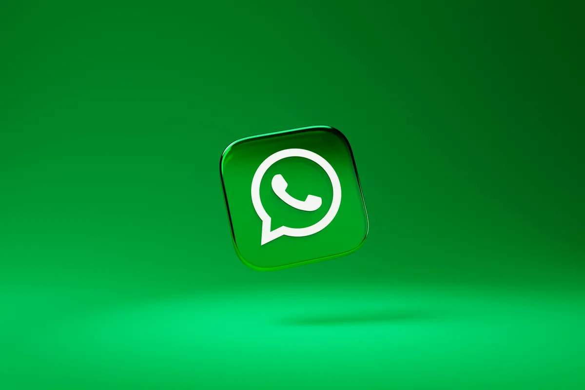 Ein gläsernes WhatsApp Logo auf grünem Hintergrund